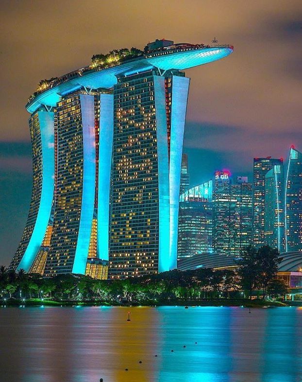 Marina Bay Sands glowing blue at dusk with the Singapore skyline across the water